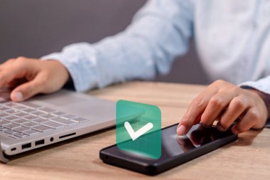 Ekranda yeşil işaretli akıllı telefon kullanan bir iş kadını. Onaylandı, onaylandı, tamamlandı, onaylandı ve onaylandı.