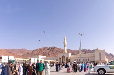 Madinah, Suudi Arabistan - 19 Aralık 2024: Uhud bölgesindeki Sayed Al-Shuhada Camii 'nin önünde arka planda Uhud Dağı olan kalabalık. Açık mavi gökyüzü.