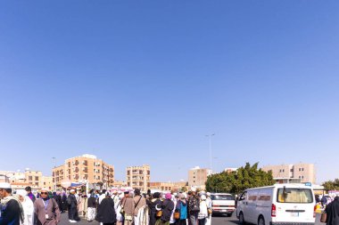 Taif, Suudi Arabistan - 15 Aralık 2024: Taif şehrinde yerleşim alanındaki binaların geçmişine sahip bir grup insan seyahat ediyor