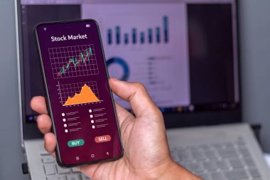 Borsa, kripto para birimi ya da veri satışı grafiklerini analiz etmek için akıllı telefon kullanan bir adam. Ticari konseptte risk yönetimi.