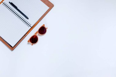 Beyaz arkaplanda bir dizüstü bilgisayar ve güneş gözlüğü