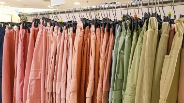 Renkli kadın pantolonları bir giyim mağazasında satılık elbise askılarına asılmış.