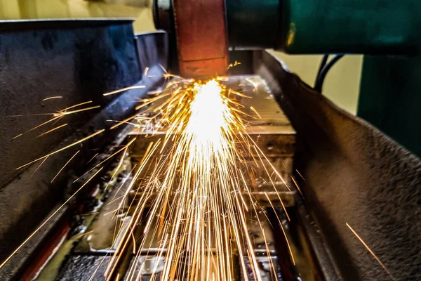 stock image Grinding metal on a machine, sparks fly into the chamber. Front view