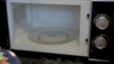 Euro banknotes on a plate in the microwave are heated and change shape when heated. A man puts a plate of European money into the oven.