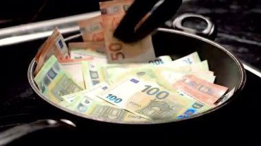 The hostess girl mixes euro bills in a frying pan in the kitchen.