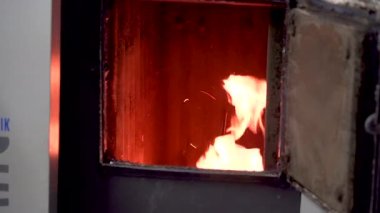 Bir adam sobayı yakacak odunla yakıyor ve ısınmak için odunları ateşe atıyor..