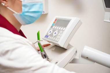 The dentist prepares for work and sets up the remote control for examining teeth.