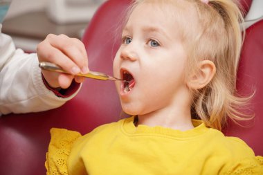 Little girl at the dentist. The doctor checks and examines the child's teeth.