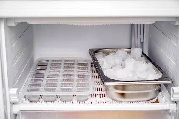 Frozen ice cubes in a stainless steel bowl in the freezer