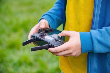 Alandaki bir çocuk bir kuadkopter fırlatır ve uzaktan kumandayla kontrol eder..