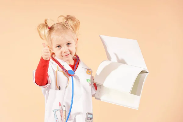 The girl doctor holds a blank notebook for notes and shows a thumbs up.