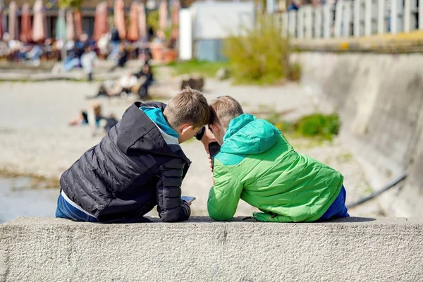 公園では１０代の少年２人が携帯電話で遊んでいる 高品質の写真 — ストック写真