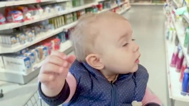 小さな子供がモールのショッピングカートに座って商品を見て回る 高品質4K映像 — ストック動画