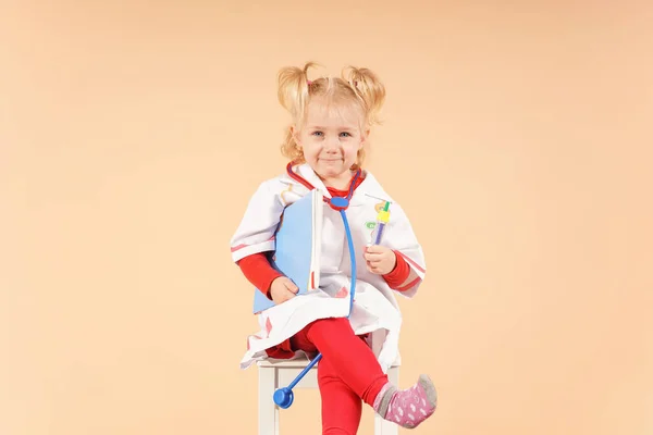 Mała Dziewczynka Stetoskopem Ubraniu Lekarza Siedzi Białym Krześle Czeka Pacjentów — Zdjęcie stockowe