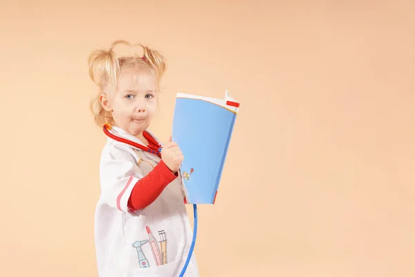 Маленька Дівчинка Стетоскопом Тримає Книжку Руках Дивиться Неї Дитячий Лікар — стокове фото