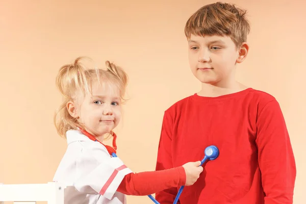哥哥和姐姐扮演医生和病人 妹妹通过儿童听诊器听她哥哥的肺 高质量的照片 — 图库照片