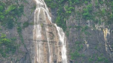 Kayalık dağların arasında şelale. Erimiş su kayaların üzerine düşer. Yüksek kalite 4k görüntü