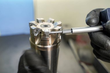 Bir işçi, CNC değirmen makinesinde çalışmak için bir değirmen kesicinin yüksek hızlı ekini değiştirir
