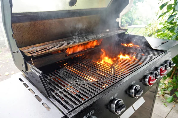 The fire of a gas grill cooks off the fat on the grill grate to cook the meat.