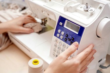 Bir kadın terzi CNC dikiş makinesine program kuruyor..