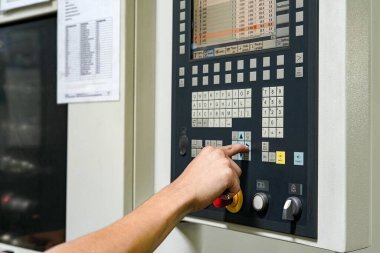 Bir işçi CNC değirmen ve torna makinesi üzerine program yazıyor. CNC programlarında hatalar denetleniyor ve düzeltiliyor.