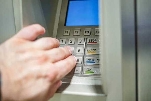 A person at an ATM enters a PIN code to withdraw cash.