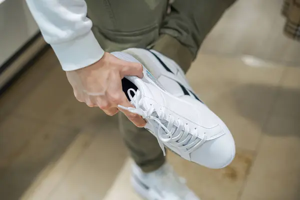 A man in a shoe store measures White sneakers in size.