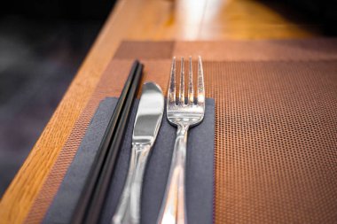 Masa bıçağı ve çatal, kafedeki bir masanın üzerindeki peçeteye konur..