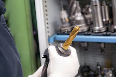 Araçları seçmek için bir işçinin elinde bir CNC makinesi için metal kesiciler.