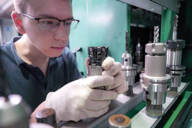 Araçları seçmek için bir işçinin elinde bir CNC makinesi için metal kesiciler.