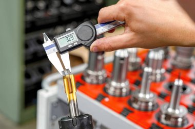 Metal işleme CNC değirmen ve dönme makineleri için bir kalibre ile kesme aracının boyutları kontrol ediliyor.