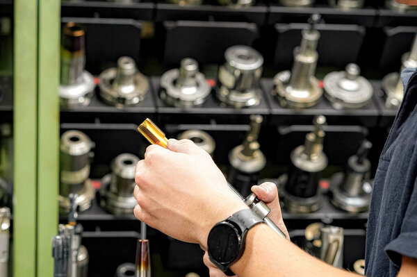 A worker in a tool warehouse inspects and selects cutters for work on a CNC milling and turning machine.