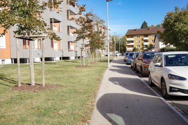 Şehirdeki çok katlı binaların yakınına park edilmiş araçlar. Şehir ve ulaşım.