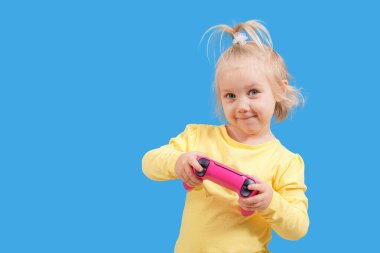 Oyun konsolundan elinde kumanda kolu olan küçük bir kız..