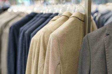 Erkek giysileri bir alışveriş merkezindeki mağazada satılık askılara asılı..