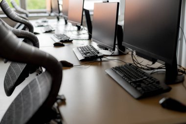 Ortaokuldaki boş bir bilgisayar laboratuvarında monitörler ve klavyeler.