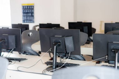 Ortaokuldaki boş bir bilgisayar laboratuvarında monitörler ve klavyeler.