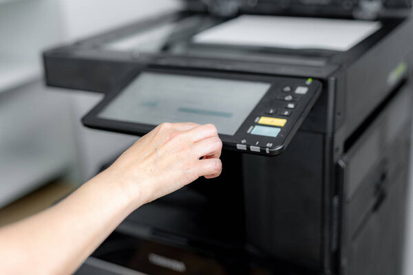 A girl sets up a photocopier to print and copy a document.