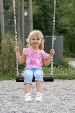 Küçük bir kız parkta salıncakta sallanıyor..
