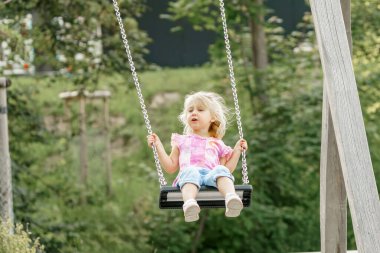 Küçük bir kız parkta salıncakta sallanıyor..