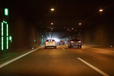 Arabaları ve gece aydınlatması olan bir yolda tünel.