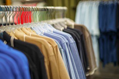 Alışveriş merkezinde satılık bir askıda farklı renklerde tişörtler..