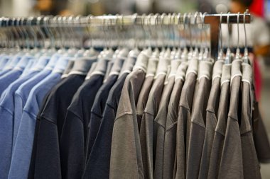 Alışveriş merkezinde satılık bir askıda farklı renklerde tişörtler..