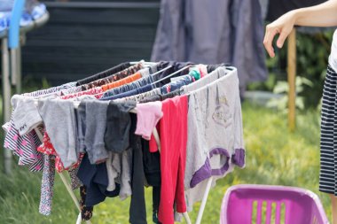 Bir kadın dışarıda kurutmak için bebek çamaşırlarını asıyor. Yıkandıktan sonra temiz çamaşır.