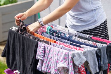 Bir kadın dışarıda kurutmak için bebek çamaşırlarını asıyor. Yıkandıktan sonra temiz çamaşır.