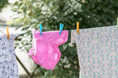 Bir kadın dışarıda kurutmak için bebek çamaşırlarını asıyor. Yıkandıktan sonra temiz çamaşır.