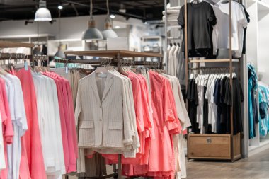 Alışveriş merkezindeki bir mağazada kadın bluzları ve ceketleri asılıydı..