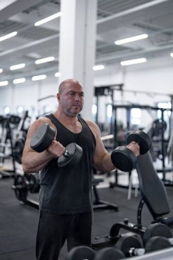 Spor salonunda pazı egzersizi yapan bir adam..