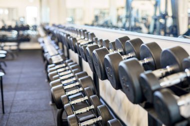 Fitness ve vücut geliştirme için spor salonundaki raflarda duran dambıllar..