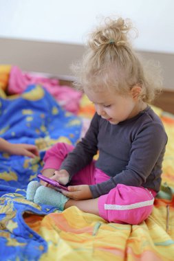 Küçük kız telefonda oynuyor.